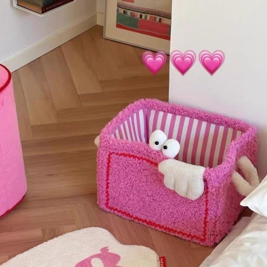 Rosa plyschtvättkorg med randigt foder på golvet