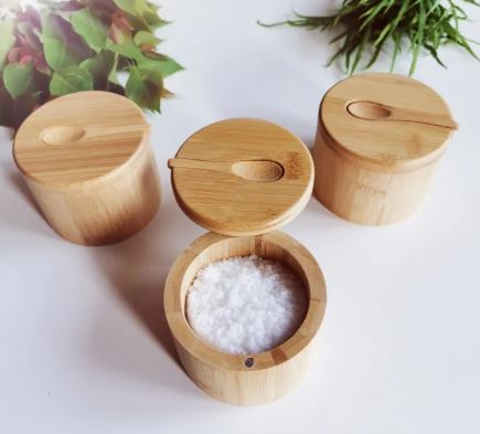 Tre kryddburkar i bambu med skedar, en öppen med salt