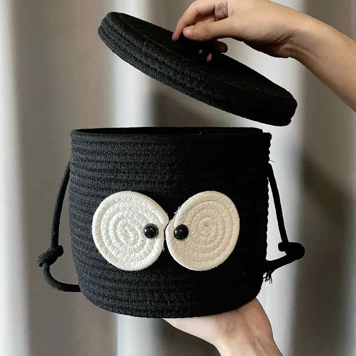 Hand som lyfter locket på en svart sotbollskorg