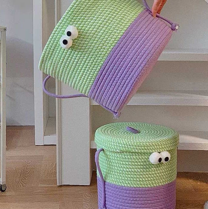 Två gröna och lila förvaringskorgar med ögon på ett golv
