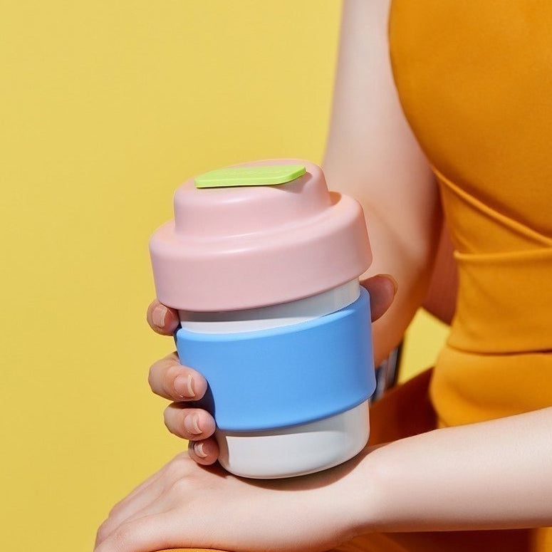 Hand som håller en rosa och blå termosmugg